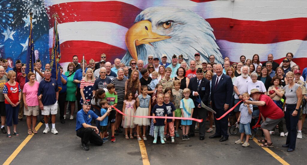 Ribbon cutting with a large group of people smiling and cheering