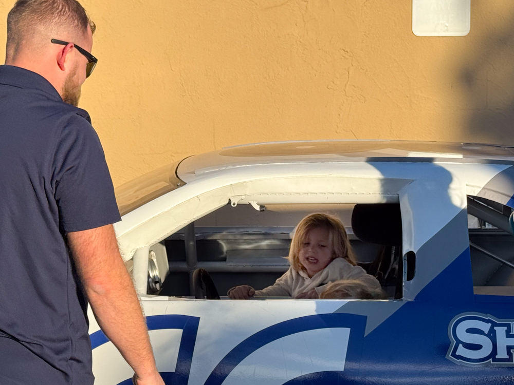 child sitting in the Shade Tree Auto race car at the Downtown Urbandale Block Party
