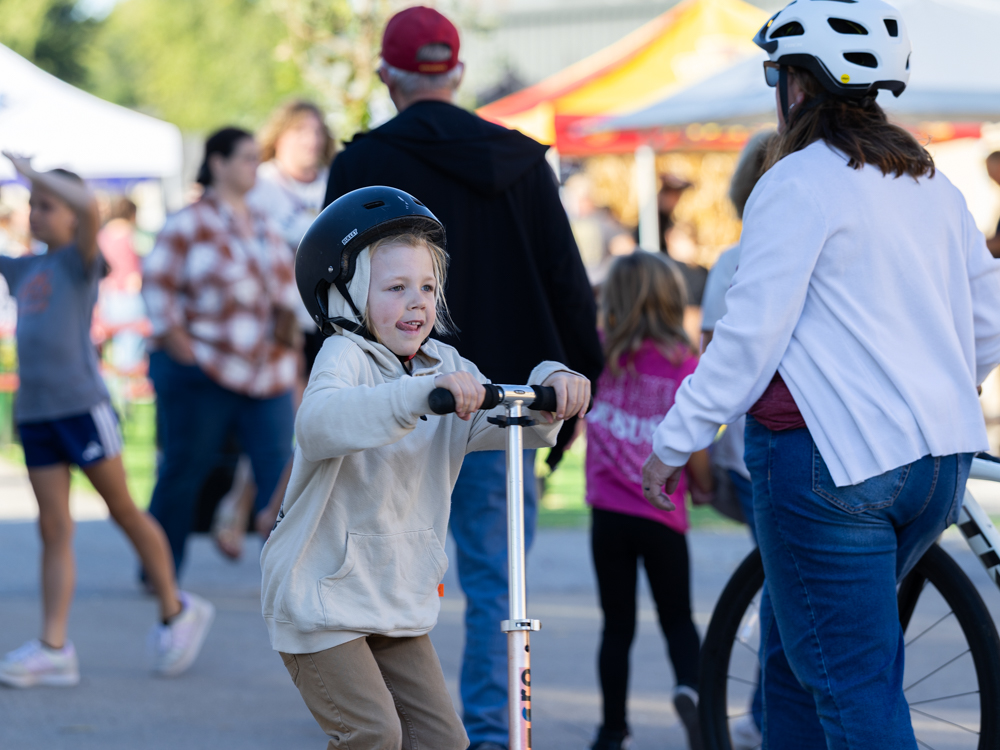 Young boy on a scoter next to a woman on a bike at the Downtown Urbandale Block Party